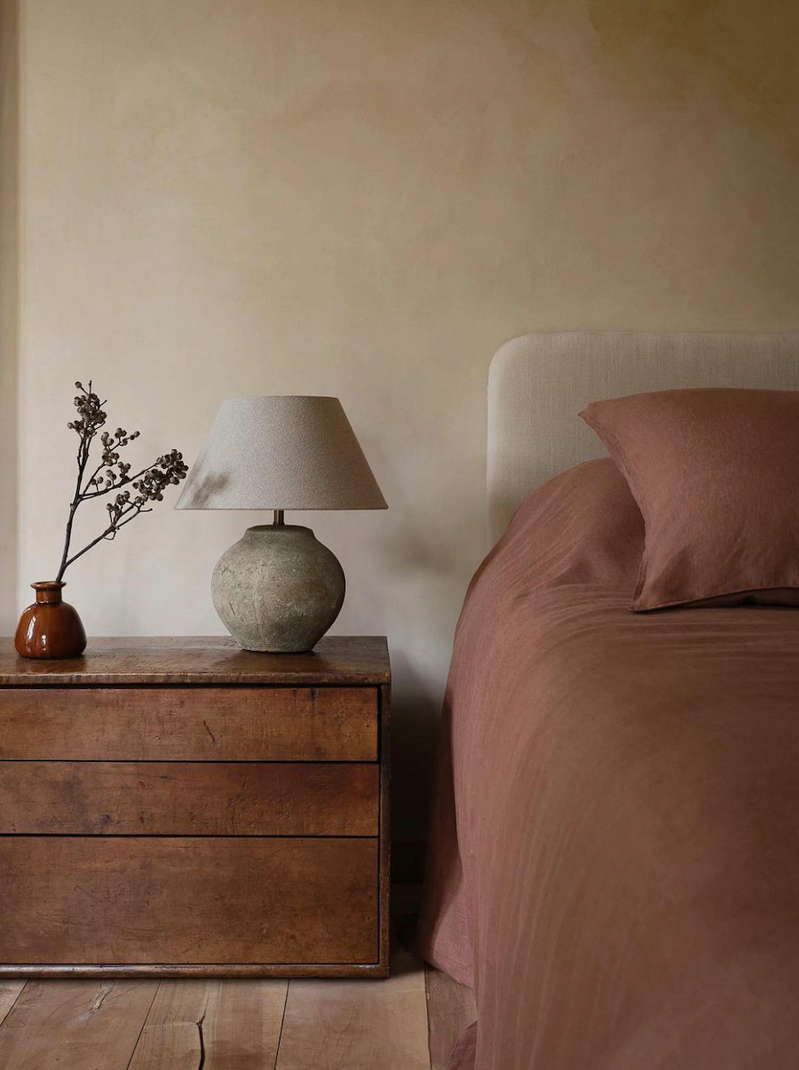 an organic modern bedroom featuring warm wood and red tones with natural elements and textures