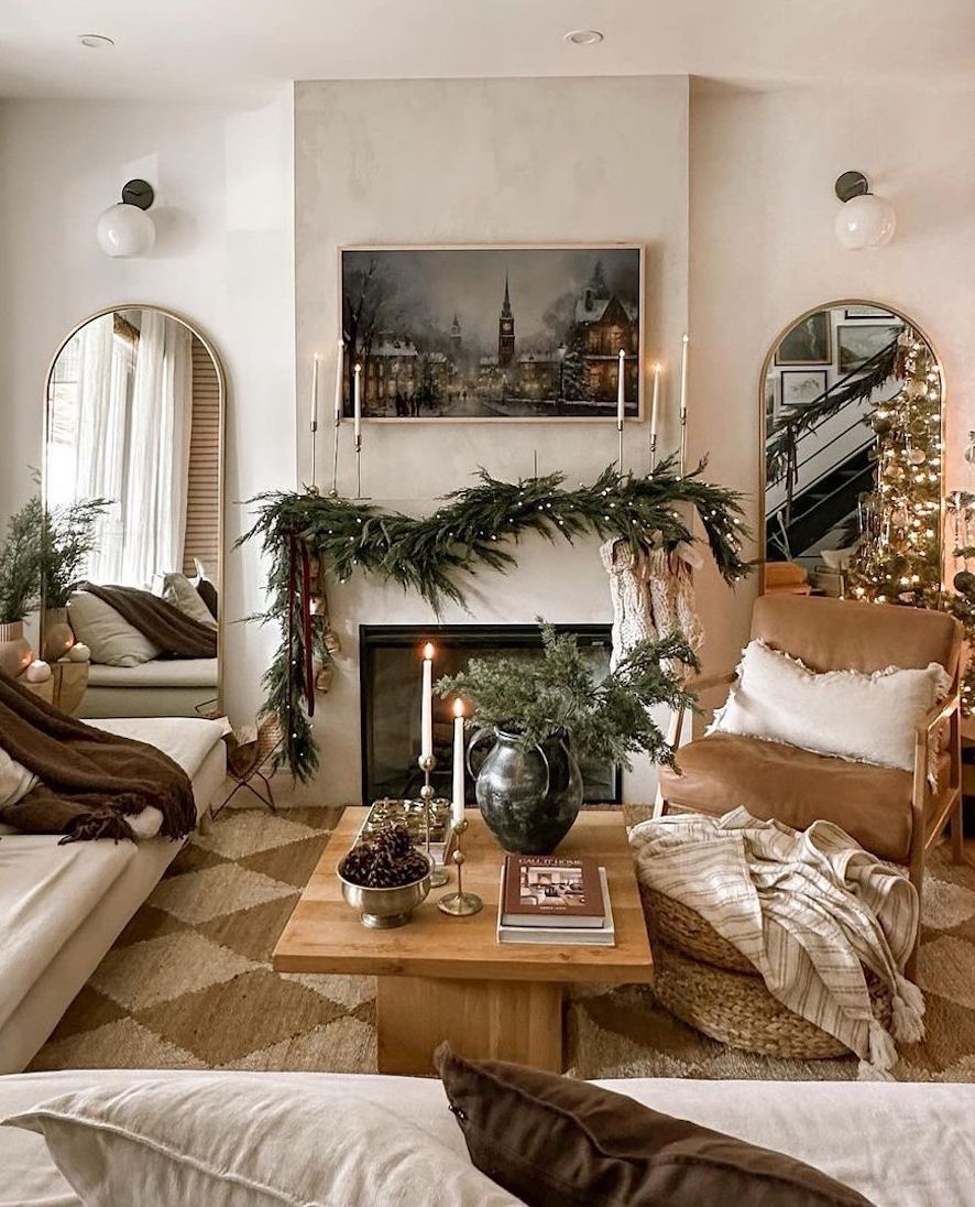 a white christmas mantle with lit pine garland, vintage candles, and antique art