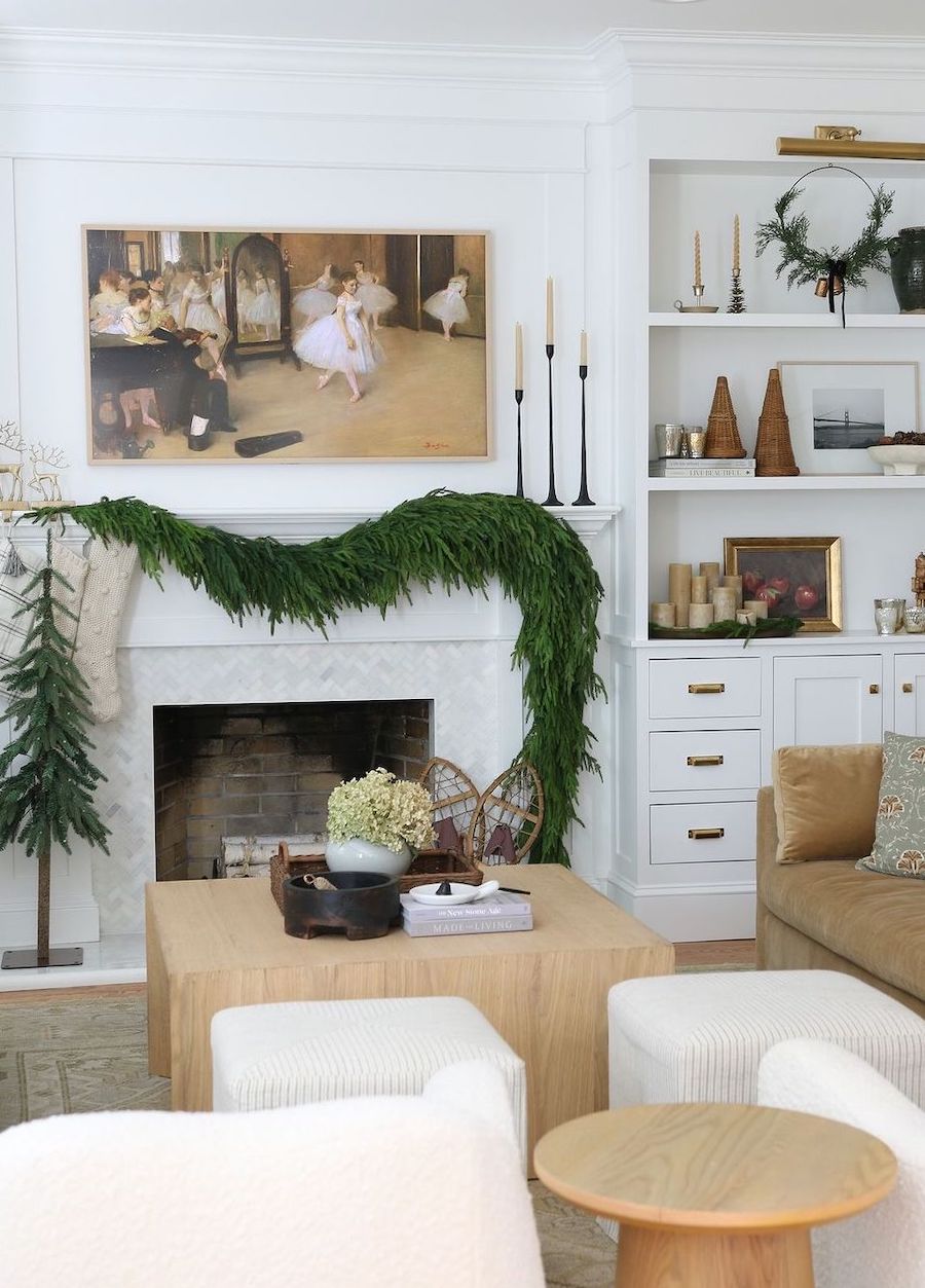 a white christmas tree with pine garland, vintage candles, knit stockings, gold reindeer, and a vintage ballet painting