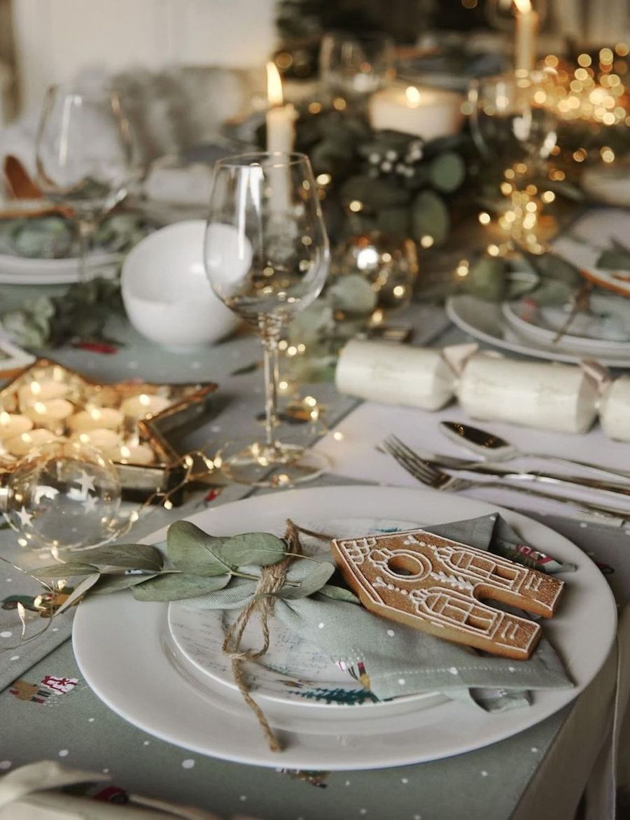 christmas table decorations featuring gingerbread cookies, soft green hues, twinkling lights, and votive candles