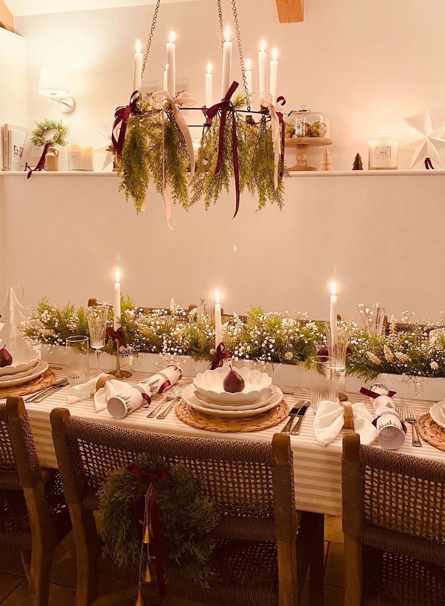 christmas table decorations featuring soft lighting, pine and baby's breath, and red ribbons