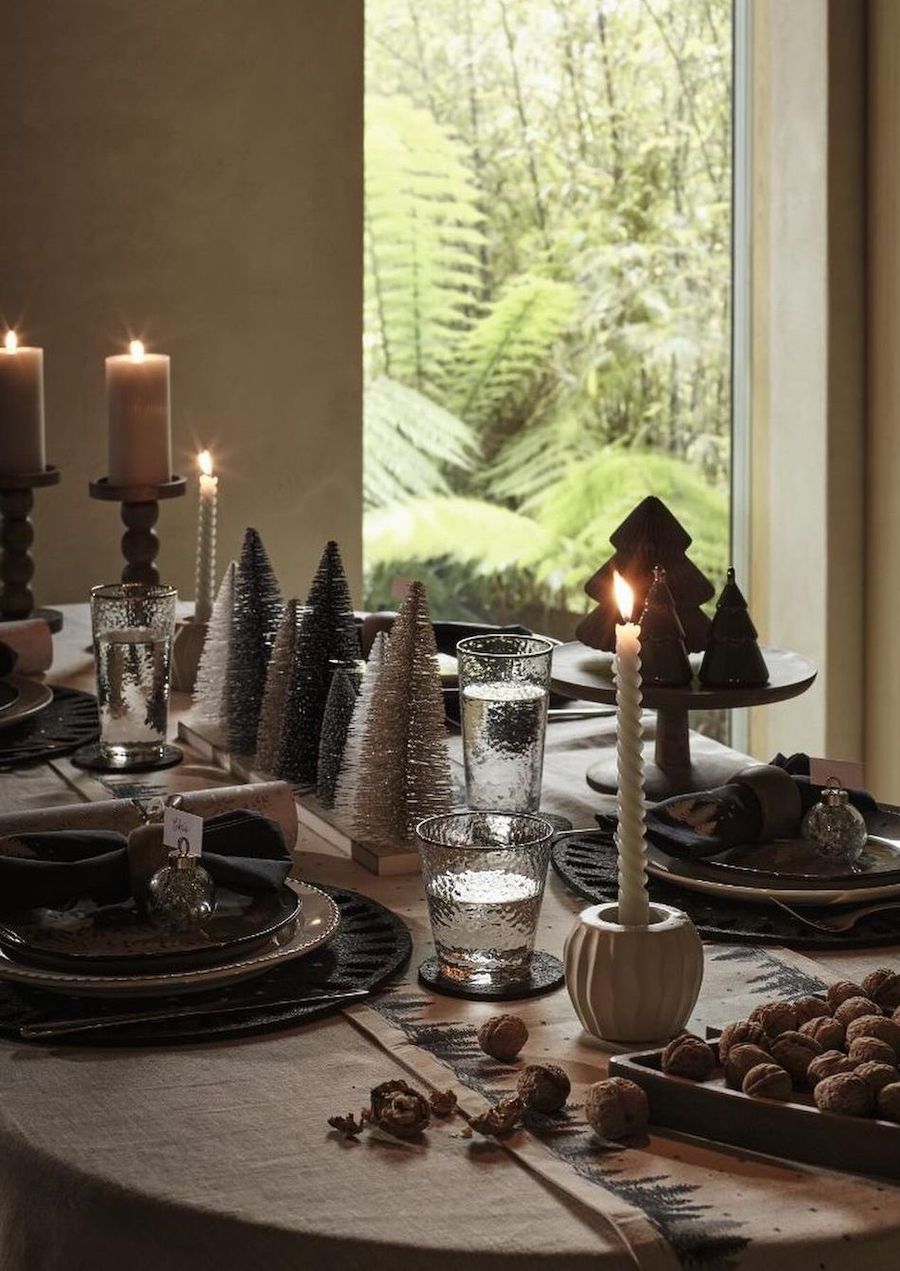 christmas table decorations featuring bottle brush trees, candles, and soft lighting