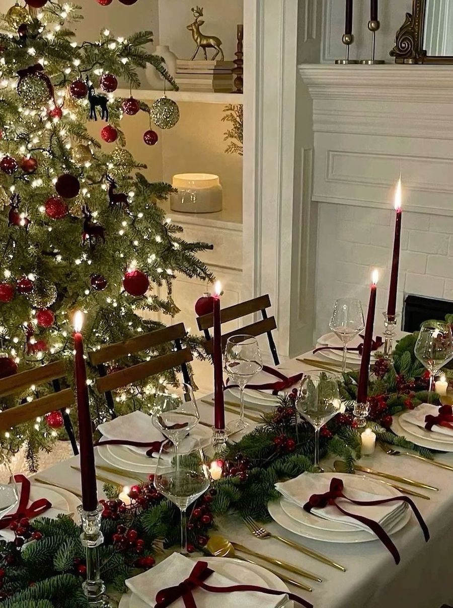 christmas table decorations featuring red berries and pine, red candles, and ribbons