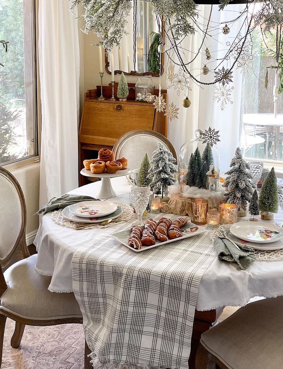christmas table decorations featuring pastries, snowy bottle brush trees, snowflakes, and plaid