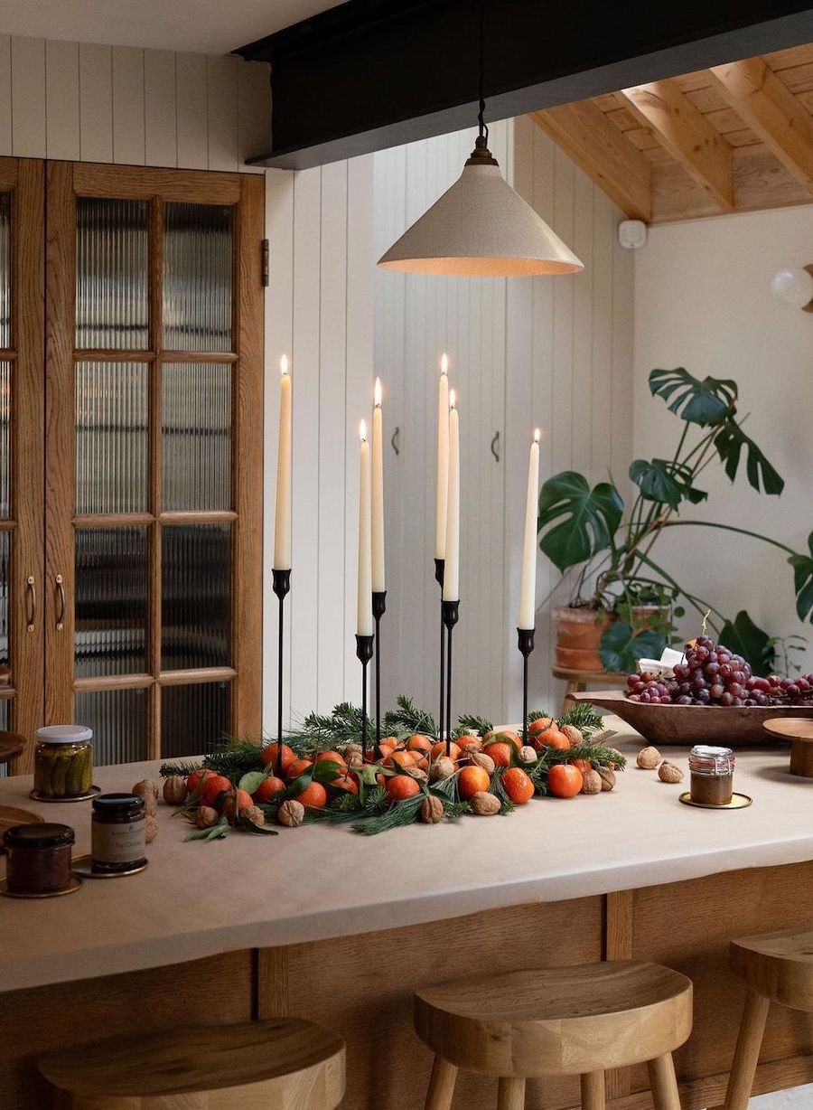 christmas table decorations featuring tall candles, pine, apples, and walnuts