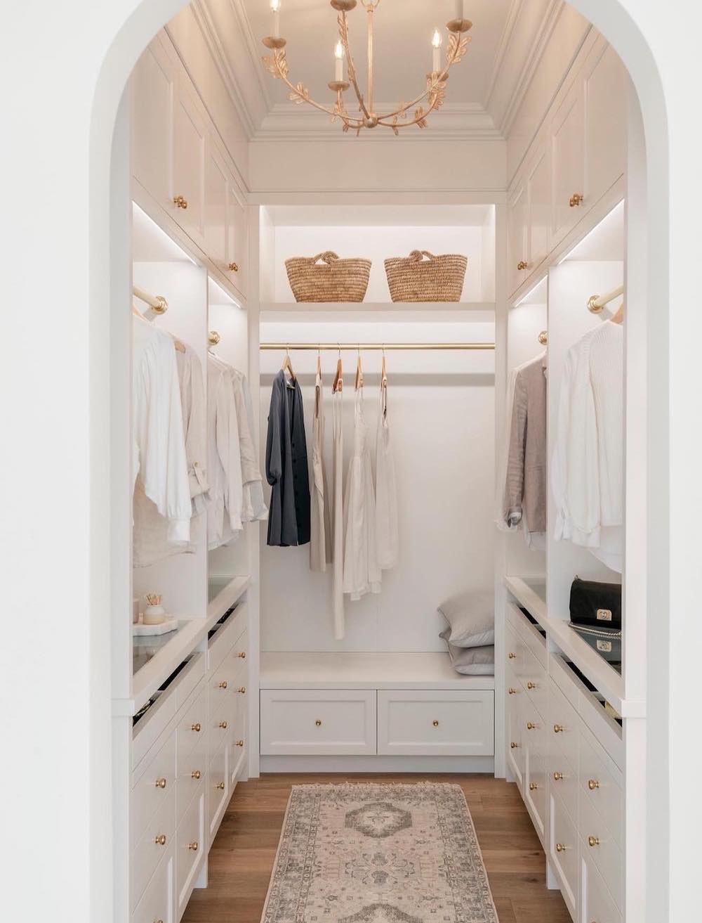 a walk in closet with built in shelves, clothing rods, and drawers