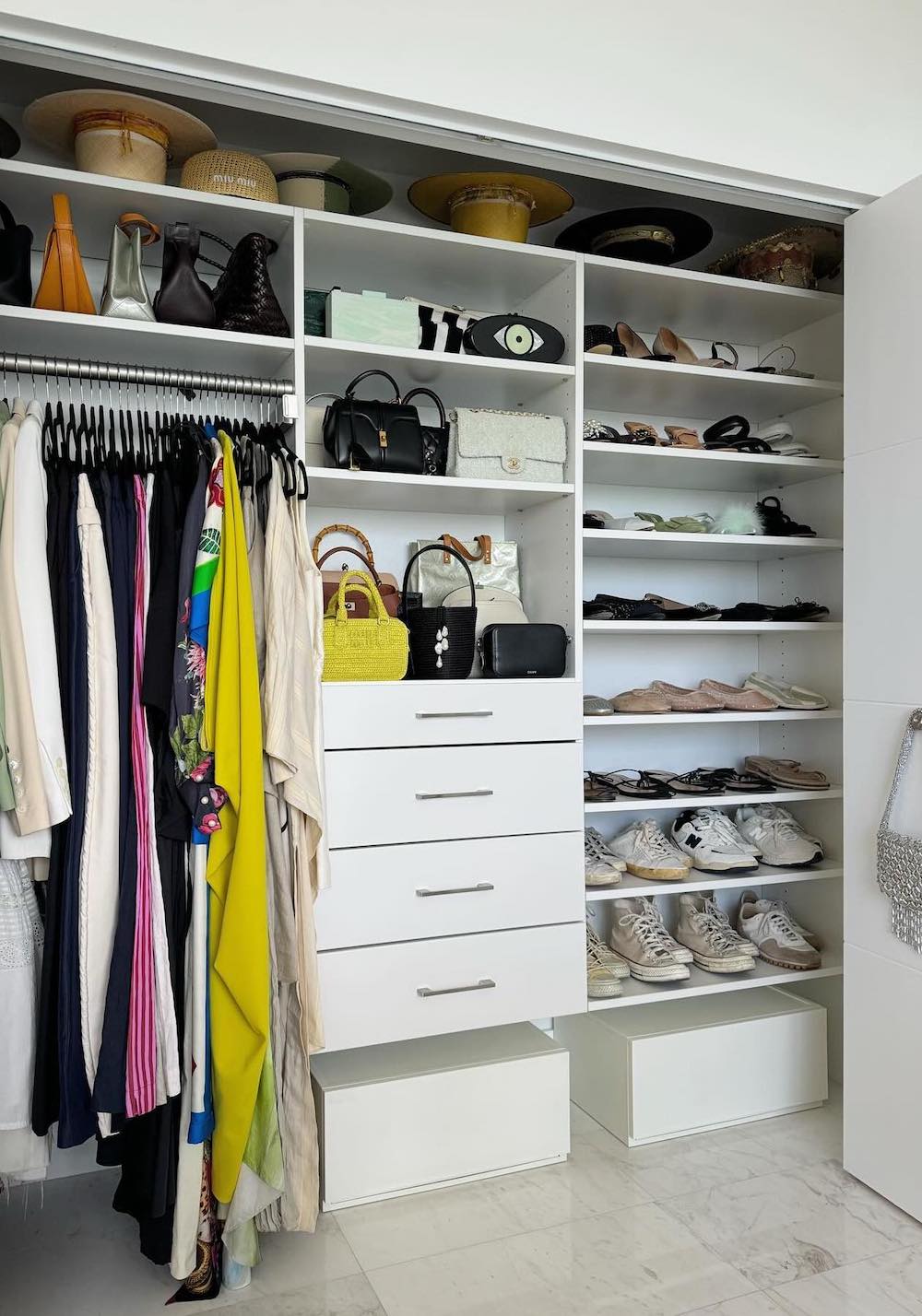 a closet with white built in shelves and drawers