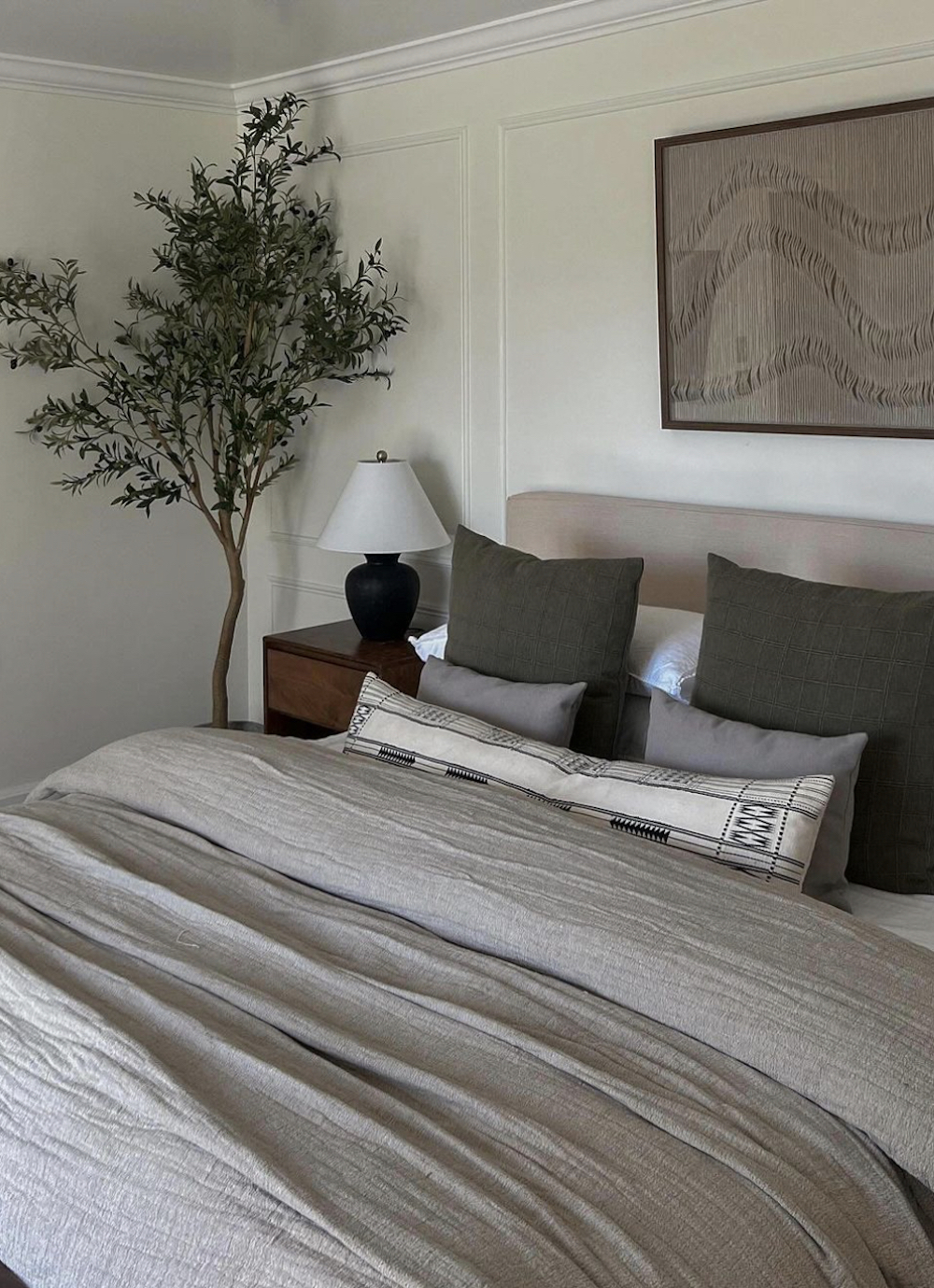 an earthy bedroom with grey and green tones and a large houseplant