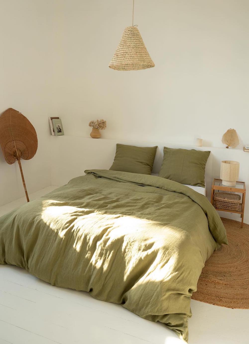 an earthy bedroom with white walls, green bedding, and boho decor