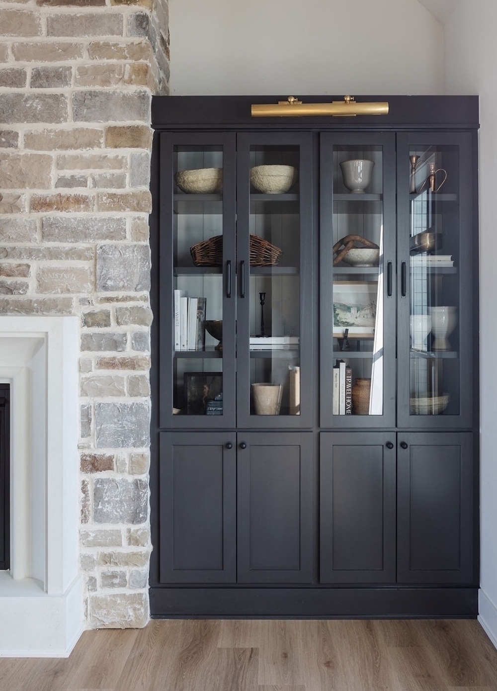 a room featuring built-in cabinet shelves next to a stone fireplace