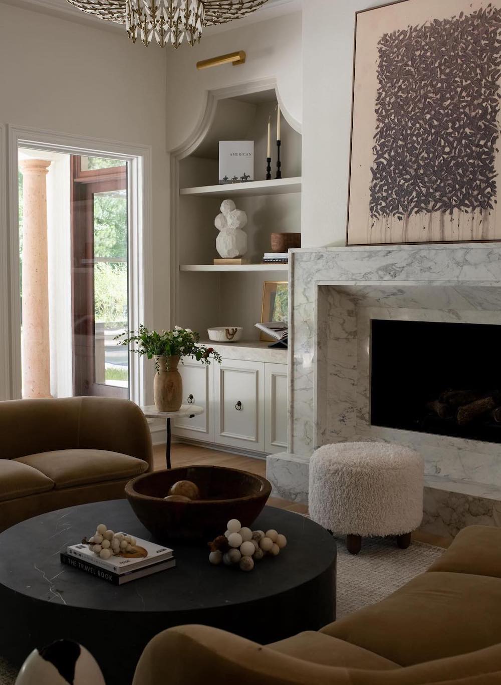 a lavish neutral room featuring built-in shelves and cabinets next to the fireplace