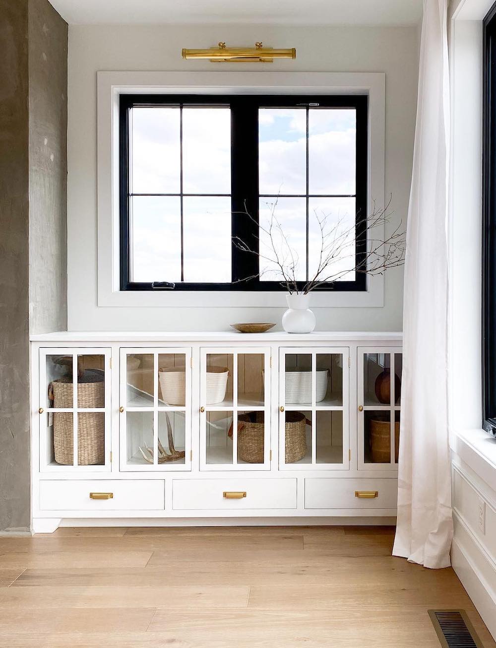 a modern neutral room featuring built-in cabinet shelves next to the fireplace