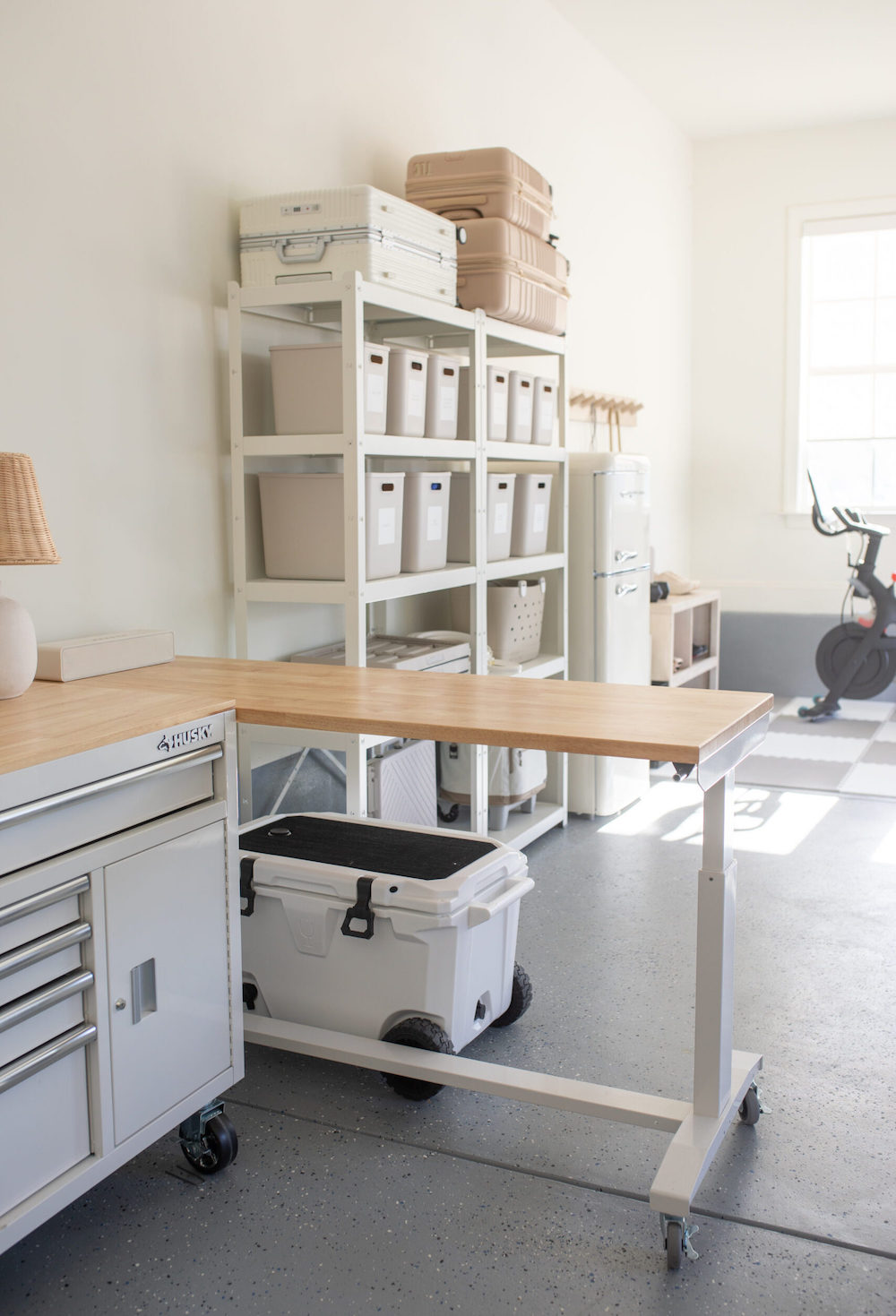 an organized garage featuring shelves, a tool bench, and a work desk