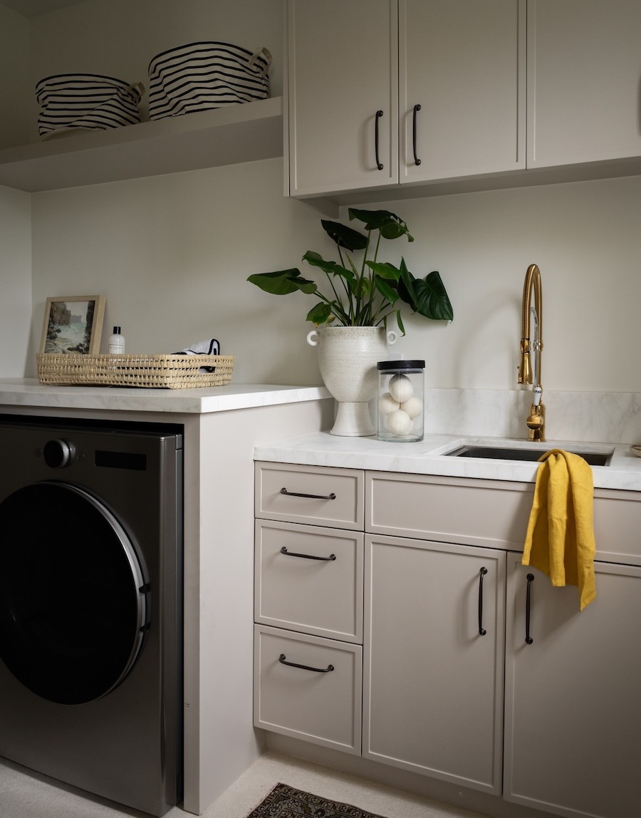 a laundry room with built-in cabinets, shelving, counters, and a sink