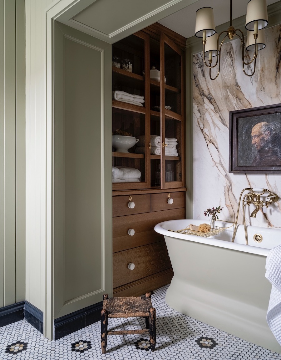 a moody bathroom with soft green walls and marble accents