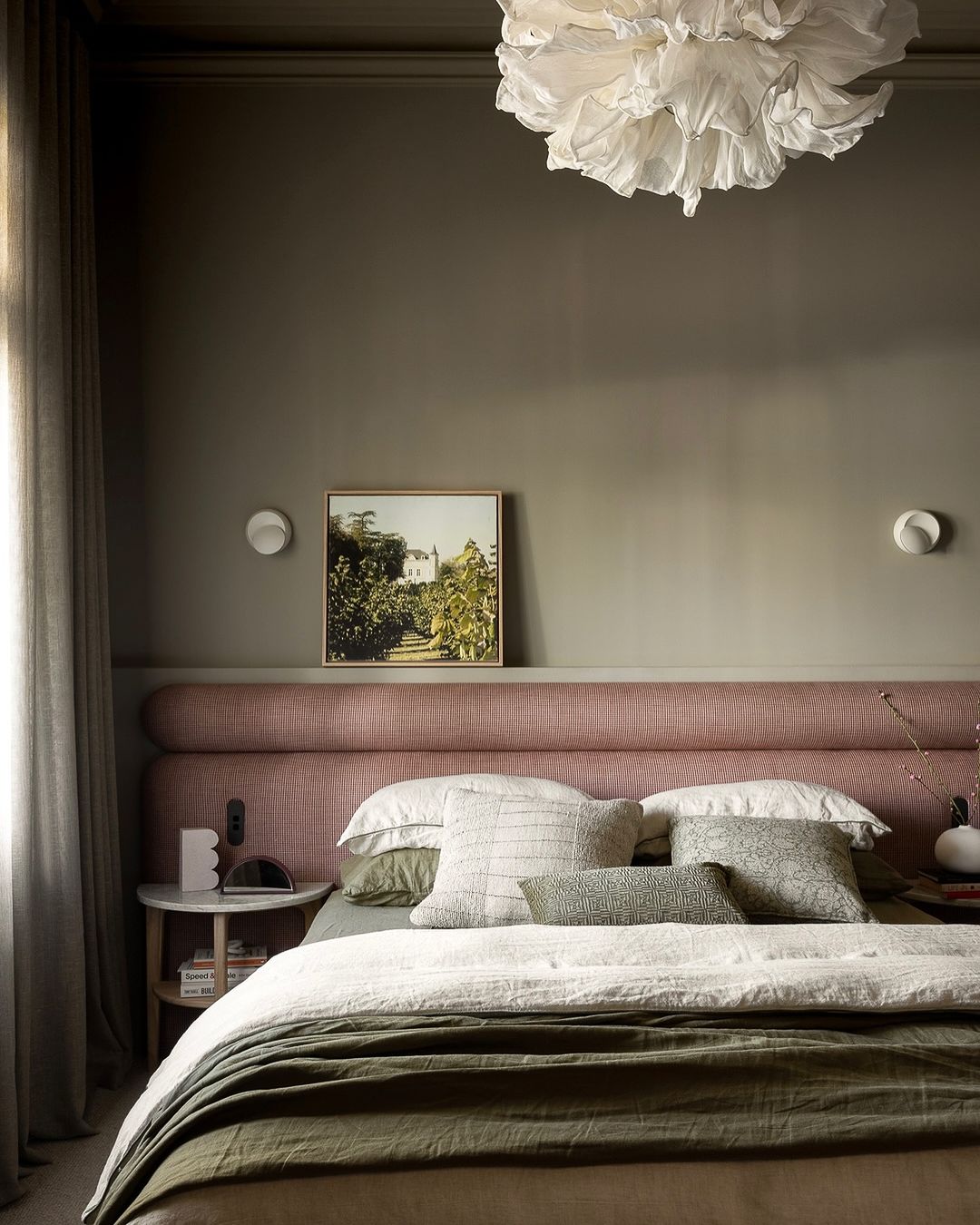 a moody bedroom featuring green and pink tones with natural decor
