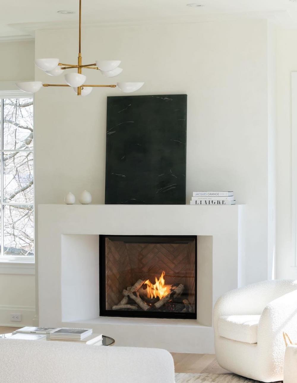 a white plaster fireplace with dark decor and pops of gold