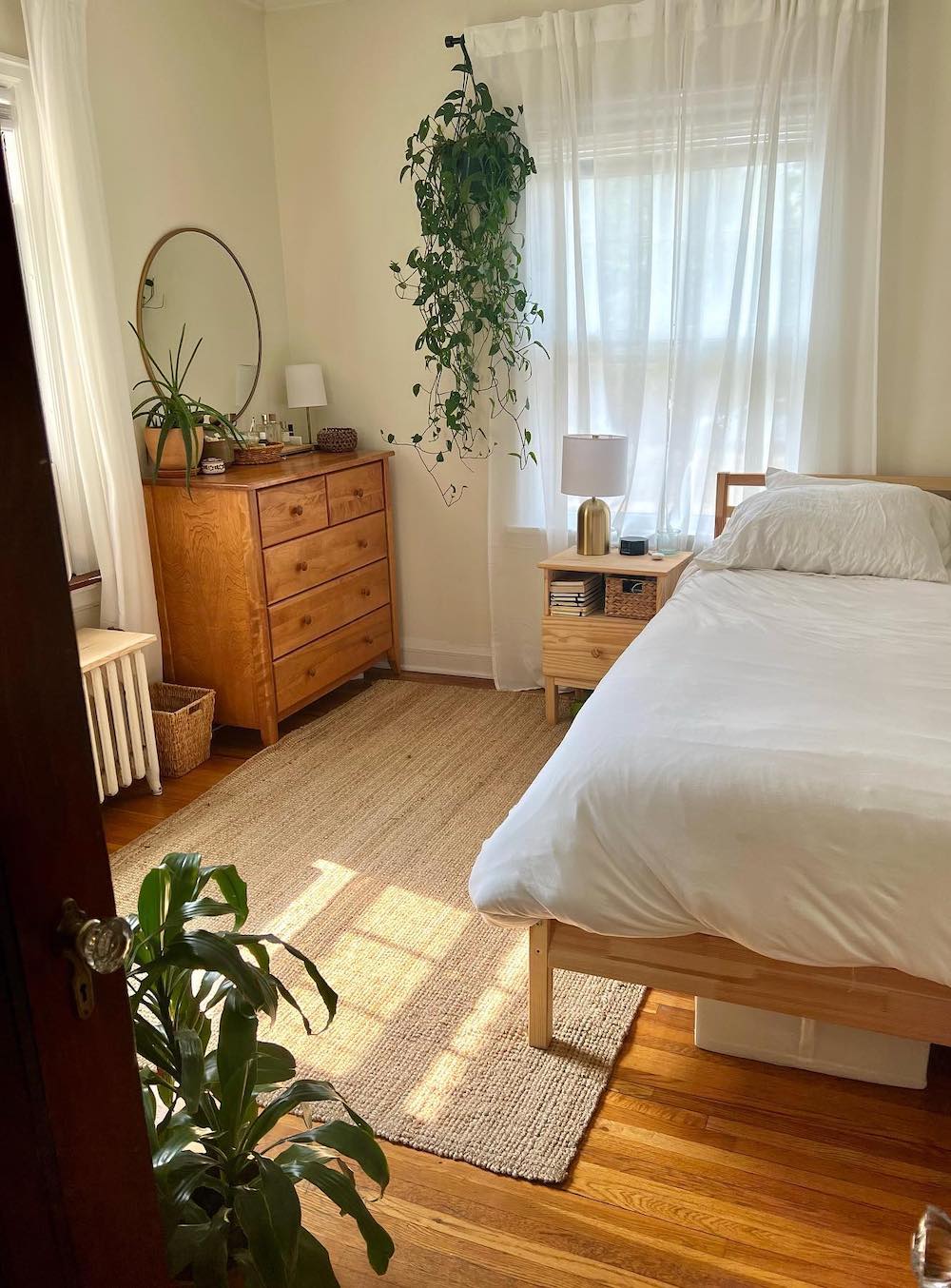 a bedroom with boho decor featuring natural wood, plants, and ivory tones