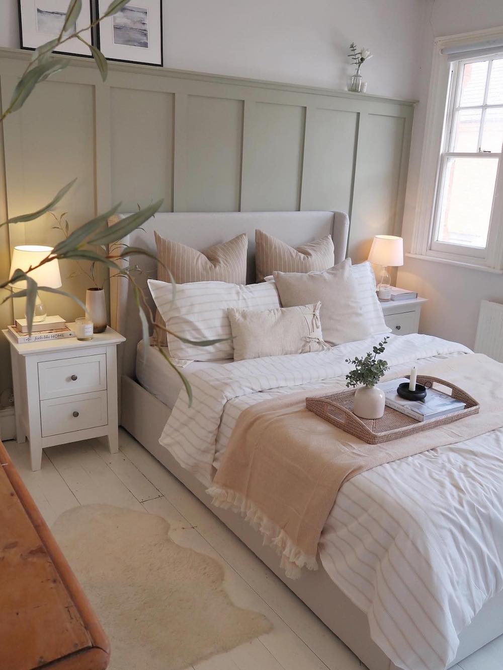 a bedroom with striped bedding, a green accent wall, and boho decor