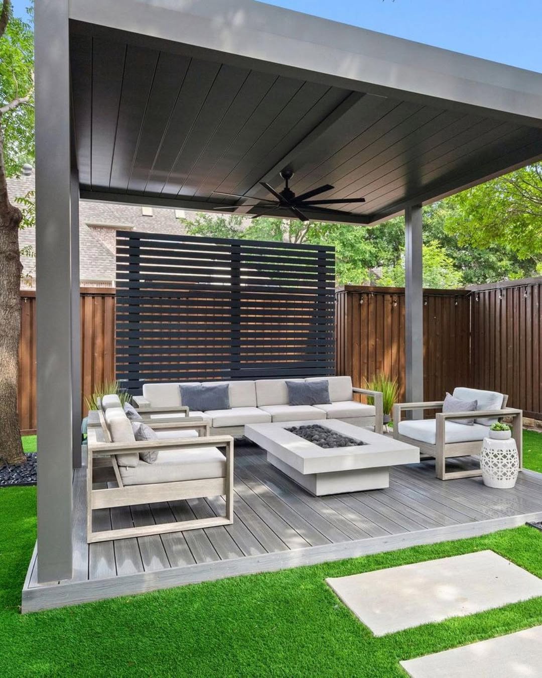Modern outdoor patio with a covered pergola, gray furniture, rectangular fire pit, and artificial grass flooring—perfect backyard inspiration for those seeking stylish pergola ideas and the ultimate outdoor destination.