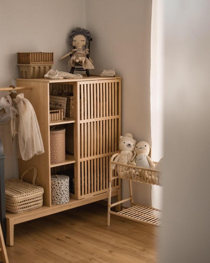 Natural bamboo storage unit from @magda.lauer with slatted doors and open shelving for nursery organization.