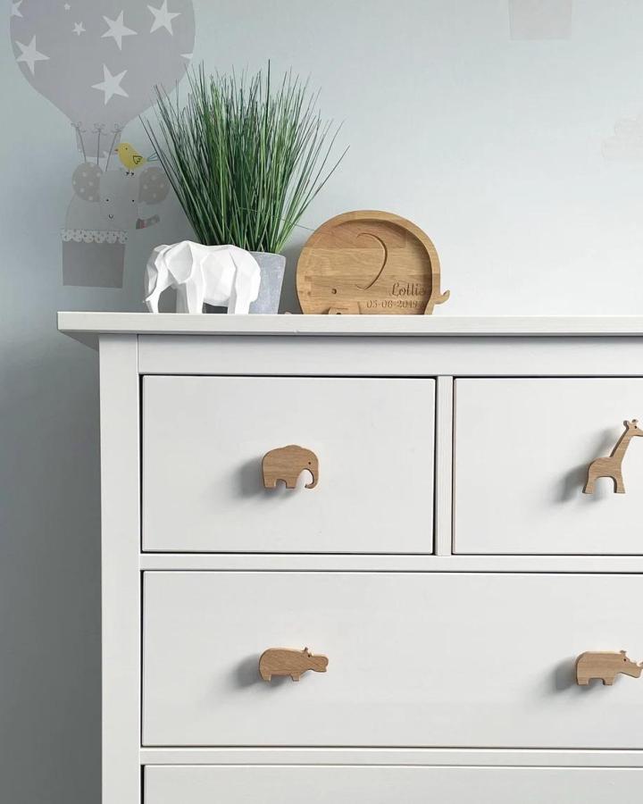 White dresser showcasing ikea baby room hacks & ideas with safari animal wooden knobs from WoodandWhistles
